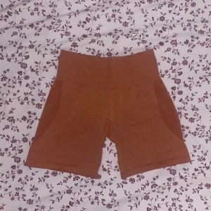 Orangea shorts från NVGTN - Orange shorts med hög midja och bred linning. Shortsen är i stretchigt material och har en tight passform som sitter bekvämt. 