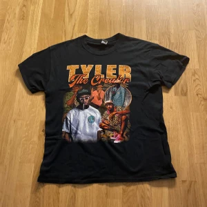 Rap T-shirt med Tyler The Creator-tryck - Cool svart T-shirt med ett färgstarkt tryck av Tyler The Creator. Perfekt för fans av artisten som vill ha en unik och stilren look. T-shirten har korta ärmar och en normal passform.