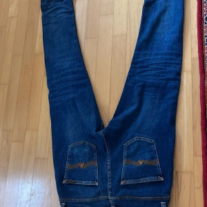 Blå jeans från Nudie Jeans - Säljer ett par snygga blå jeans från Nudie Jeans. De har en klassisk femficksdesign och en bekväm passform. Perfekta för en avslappnad stil.