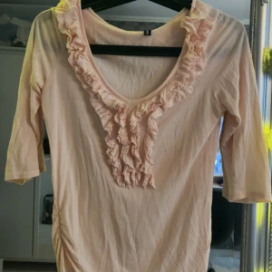 Ljusrosa topp med volangdetaljer - Säljer en ljusrosa topp med volangdetaljer, endast använd 2 gånger Från Madonna 