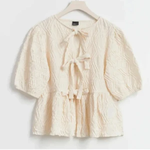 Beige blus från Monki - Fin beige blus från med korta ärmar och knytband framtill. 