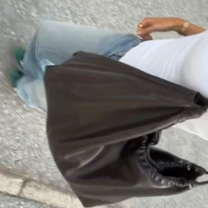Mörkbrun axelväska med kedjedetalj  - Snygg mörkbrun axelväska i skinn med en elegant kedjedetalj på axelremmen. Väskan har en mjuk och slouchy design som ger en avslappnad men stilren look. Perfekt för att bära dina dagliga nödvändigheter med stil, perfekt till skola eller jobb!🤍