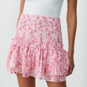 Rosa volangkjol med smock - Supersöt kortkjol i rosa . Kjolen har ett blommigt mönster och är gjord i ett lätt, luftigt material som ger en flowy känsla. Perfekt för en somrig look! Köpt på Gina tricot och är som ny. Kan gå ner i pris vid snabb affär.🌸