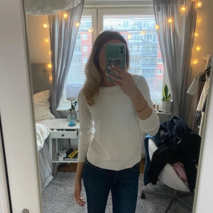 Vit stickad tröja - Säljer en stilren vit stickad tröja med rund hals och långa ärmar. Perfekt för en avslappnad look. Tröjan har ribbade muddar vid ärmslut och nederkant.