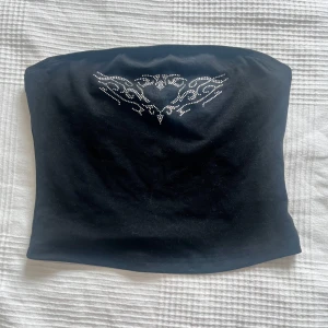 Svart bandeau tubtopp med strassdetalj - Svart bandeau tubtopp med snygg tribal-inspirerad strassdekor 
