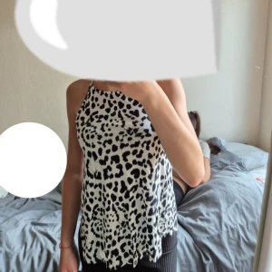 Leopardmönstrad linnetopp Gina Tricot - Säljer en snygg ärmlös linnetopp från Gina Tricot i storlek XS. Toppen är vit med svart leopardmönster och har smala axelband och rak halsringning. 