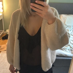 Beige stickad kofta med loose fit - Mysig beige stickad kofta med avslappnad, loose passform och långa ärmar. Koftan är öppen framtill och har en enkel, stilren design som passar perfekt till lager-på-lager. Superenkel att slänga på över vilken outfit som helst.
