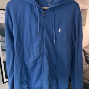 Polo Ralph Lauren zip upp hoodie - Jag vill sälja min polo tröja, denna köpte jag för ett år sedan och använt en gång. Den är som ny, finns inget tecken på att jag ens använt den och vill därför sälja den. Har orderbekräftelse kvar.