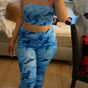 Multifärgat sett - Säljer ett matchande sett i blått med coolt mönster som påminner om marmorerade vågor. Toppen är axelbandslös och sitter tight över bröstet, perfekt för dig som vill sticka ut med färg och form. 