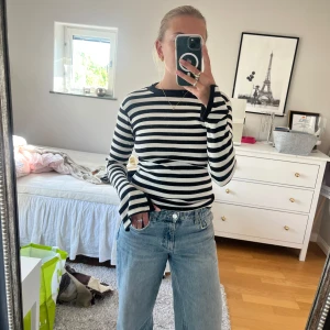 Svartvit randig långärmad tröja - Säljer en svartvit randig långärmad tröja med tight passform och rund hals. Tröjan har breda ränder och är i ett mjukt, ribbat material som sitter snyggt på kroppen. Perfekt att styla med jeans för en clean och stilren look.