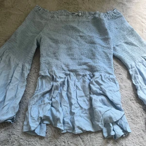 Ljusblå offshoulder blus från Ellos - Supersöt ljusblå blus från Ellos med offshoulder-modell och långa, vida ärmar. Som ny är tröjan.