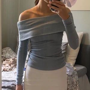 Ljusblå offshoulder topp - Supersnygg ljusblå offshoulder topp med lång ärm och tight passform. Toppen har en bred, vikt kant över axlarna som ger en cool och trendig look. 