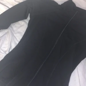 Svart tight kofta från Gina Tricot XS - Säljer en svart, figurnära jacka från Gina Tricot i storlek XS. Jackan har hel dragkedja framtill, långa ärmar med tumhål och är tillverkad i ett stretchigt material som sitter snyggt på kroppen. Perfekt för en sportig och stilren look. Mötts bara up och tar bara kontant!!