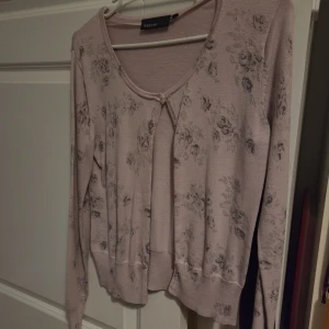 Rosa kofta - En puderrosa kofta med grått blommigt mönster från Kappahl.