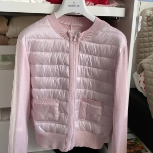 Ljusrosa dunväst från Gina Tricot - Supersöt ljusrosa cardigan från Gina Tricot med quiltad framsida, två fickor och ribbade muddar. Västen har dragkedja hela vägen och är i en mix av syntet och stickat material. Perfekt för lager-på-lager och en chill look som liknar den populära cardiganen från Moncler! Storlek 170 men passar även xs/s dam