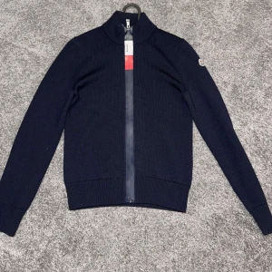 Stickad Moncler tröja - Säljer denna feta mörkblåa stickade Moncler tröjan. Tröjan är bara använd ett fåtal gånger och är därför i bra skick. Den är storlek 164cm. Självklart äkta, men kvitto saknas Pris kan diskuteras