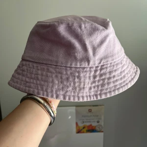 Ljuslila bucket hat från Lindex - En ljuslila bucket hat från Lindex. Klassisk form med nedvikt brätte och diskret sömstruktur runt om. Färgglad. 