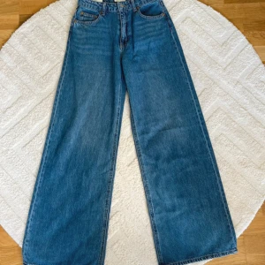 Wide high waist jeans från H&M - Blåa wide leg jeans från H&M med hög midja. Klassisk femficksmodell med raka, vida ben och snygg denimtvätt. Perfekta för en chill och trendig look. Helt ny