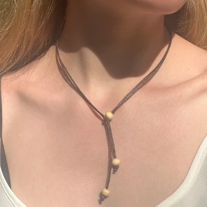 Handgjort halsband av konstläder med träpärlor - Letar du efter ett halsband som är både snyggt, enkelt och unikt? Då har du kommit rätt! Jag säljer mina handgjorda halsband i konst-läder med träkulor. Varje halsband handgjort med omtanke och blir därför helt unik!  Längden går att justera för att få den precis så som du vill ha den, jag kan också tillverka olika längder. Men den som visas på bilden är 45 cm lång i sitt ”maxläge”.   Fråga gärna om du vill se fler bilder eller har några frågor! 