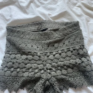 Grå/gröna spetsiga shorts från Gina Tricot - Supersnygga khaki färgade  shorts från Gina Tricot i storlek 36. De är i spets. Perfekta för sommarens varma dagar och ger en bohemisk vibe till din outfit. Aldrig använda. 