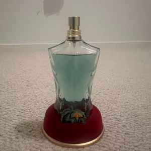 Jean Paul Gaultier Le Beau Paradise Garden - Säljer en Jean Paul Gaultier Le Beau Paradise Garden parfym i en unik flaska formad som en manlig torso. Flaskan är grön och står på en röd bas. Förpackningen är dekorerad med tropiska blommor och blad. Innehåller 75 ml av doften. Nästan helt oanvänd!