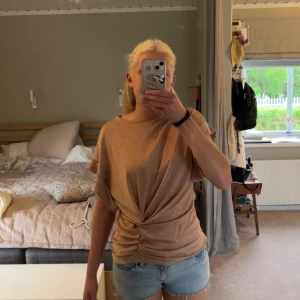 Glittrig beige topp  - Säljer en glittrig beige topp från Valerie med korta ärmar och snygg twistad detalj framtill. Vet ej storlek men tror att det skulle passa       S-M.Toppen är perfekt till fina festtillfällen! Pris kan alltid diskuteras🩷