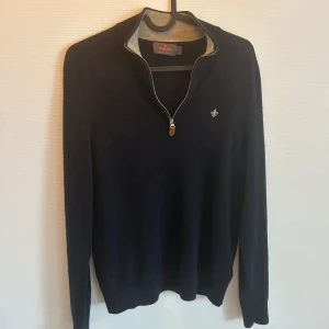 Mörkblå halvziptröja Morris - Mörkblå stickad tröja från Morris med halv dragkedja och liten broderad logga på bröstet. Perfekt för lager-på-lager och snygg till jeans. Tröjan passar bra på mig som är S, men den sitter tight. Funkar bra till XS också