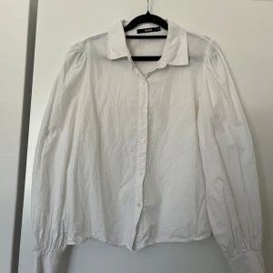 Vit skjorta med puffärm från Bik Bok - Vit skjorta från Bik Bok med klassisk krage, puffiga långärmar. Visa missfärgning under armar efter deo, inget som syns vid användning.