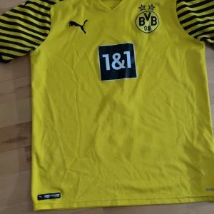 Borussia Dortmund Haaland tröja Puma - Gul Borussia Dortmund matchtröja från Puma med svarta ränder på ärmarna, klubbmärke och sponsortryck framtill. På ryggen står det Dortmund, nummer 9 och Haaland. Köpt från dortmunds egna shop. Kvitto går nog att få fram efter letande men fick i julklapp. Storlek small och knappt använd m. Tvättar innan ja skickar iväg.