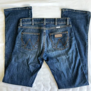 Wrangler lågmidjade bootcut jeans  - Snygga blå jeans från Wrangler med låg midja och bootcut. Storlek W27 L32, midjemått 38cm rakt över och innerbengslängd 85cm. Tyvärr för små för mig så kan inte skicka bild på🩷