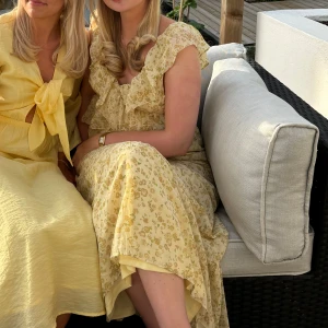 Gulblommig långklänning med volang - Superfin långklänning i ljusgul nyans med små blommor och volangdetaljer vid axlar och urringning. 🩷