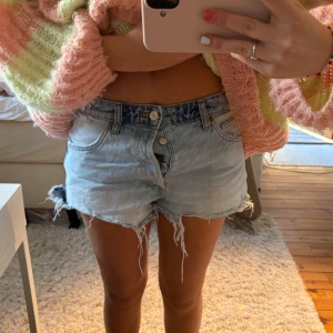 Ljusblå jeansshorts - Säljer ett par ljusblå jeansshorts med råa franskantade benslut med en låg midja. Fram på shortsen är de ljusa i färgen och bak är det lite mer mörka💙shortsen är i storlek 38 men skulle säga att den sitter mer som en 36