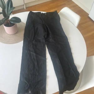 Svarta kostymbyxor från STOCKH LM - Svarta kostymbyxor från STOCKH LM med klassisk passform och raka ben. Byxorna har hällor för bälte, diskreta bakfickor och stängs med dragkedja och hake. Perfekta för en stilren look.