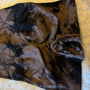 Svarta och gråa tie-dye leggings - Säljer ett par snygga shorts med svart och grått tie-dye mönster. De är stretchiga och sitter tight, perfekta för träning eller en avslappnad look. Hög midja för extra komfort.