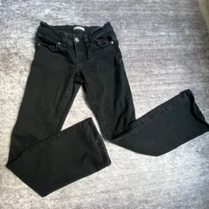 Svarta jeansbyxor me bootcut + lowwaist - Svarta jeansbyxor med utsvängda ben och klassisk femficksdesign. Byxorna har knapp och dragkedja framtill samt fickor med lock och knapp bak. Perfekta för en stilren och enkel look. Säljer dom för nästan fullpris eftersom att dom är använda en gång.