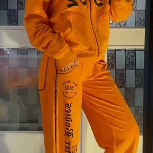 Better Bodies mjukis sett - Säljer ett par orange mjukisbyxor med svart tryck längs benet och på låret. Byxorna har en avslappnad passform och resår i midjan. Perfekta för en chill och bekväm stil.