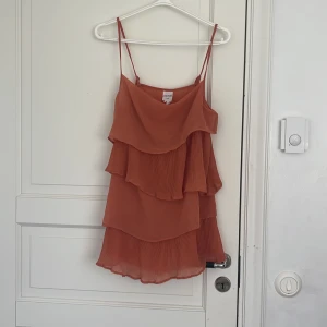 Orange volangig klänning från Monki - Säljer en orange klänning från Monki med flera lager volanger. Superfin och kommer tyvärr inte till användning!🫰