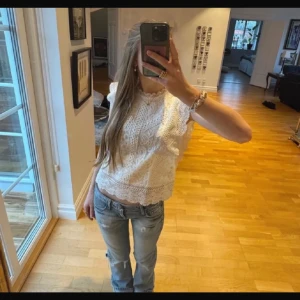 Vit spetsblus med volangdetaljer - Säljer en söt vit blus i spets med volangdetaljer längs ärmhålen och nederkanten. Blusen är ärmlös och har ett vackert mönster i spets, perfekt för en fräsch look. Perfekt till vardag och fest. Använd varsamt ca 3 gånger och inga fläckar eller defekter. Lite kort för mig som är 175 ( kan skicka bild på) nypris:450kr 