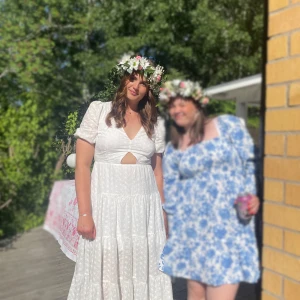 Vit klänning med puffärm och öppen rygg - Lång vit klänning med broderade blommor, puffärmar och v-ringning. Klänningen har öppen rygg med stor rosett och knytning. Klänningen är endast använd 1 gång och är nytvättad. Strl 44 men passar en strl 42, nypris 1100kr. 