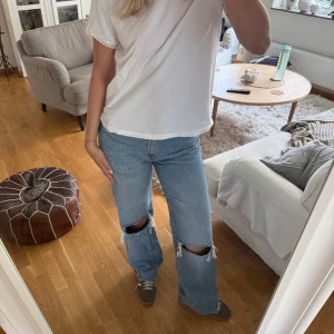 Ljusblå jeans med hål på knäna - Säljer ett par ljusblå jeans med raka ben och stora slitningar över båda knäna. 