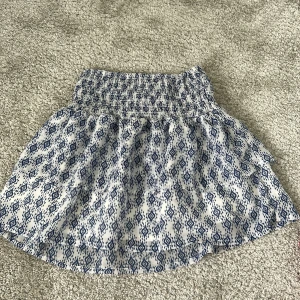 Vit och blå mönstrad kortkjol - Supersöt kortkjol med blått geometriskt mönster på vit botten. 