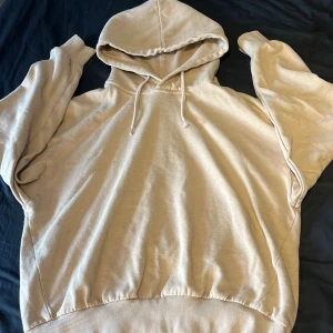 Beige hoodie från 157 - Säljer en beige hoodie från 157 i storlek S. Tröjan har huva med dragsko och ribbade muddar vid ärmslut och nederkant. Perfekt för en avslappnad och bekväm stil. Ett snöre är lite sönder 