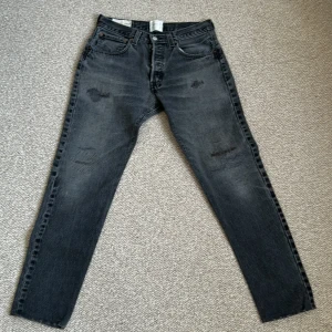 Svarta gallery dept Levis 501 jeans - Säljer ett par svarta gallery dept Levis 501 jeans med klassisk femficksdesign och raka ben. Jeansen har slitna detaljer framtill och en vintage tvätt som ger en cool look. Passar perfekt till en avslappnad stil.