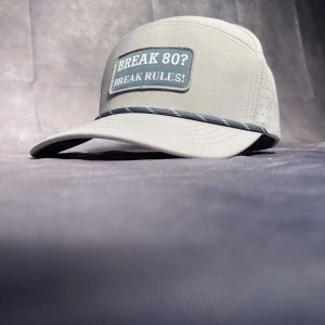Ljusgrå keps med textbrodyr - Snygg ljusgrå keps med böjd skärm och patch framtill med texten 'BREAK 80? BREAK RULES!'. Kepsen har perforerade sidor för extra ventilation och ett dekorativt band ovanför skärmen.