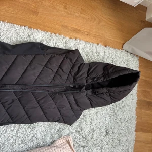 Svart väst från Zara - Säljer en svart dunväst från ZARA med huva och dragkedja framtill. Den är liten i storleken så den passar S/Xs/xxs Använd få gånger och den har inga skador eller märken, pris kan diskuteras 