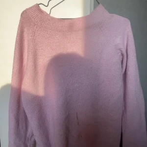Ljusrosa stickad tröja från Vero Moda - Mysig ljusrosa stickad tröja från Vero Moda. Tröjan har lång ärm och bred ribbad kant vid halsen. Perfekt för lager-på-lager och passar till både jeans och kjol) (En fläck på tröjan) Annars perfekt