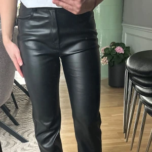 Svarta skinnbyxor med rak passform - Snygga svarta byxor i skinnimitation med raka ben. Jätte fina men lite för stora för mig. Använd några få gånger. Dessa är ifrån Gona tricot.