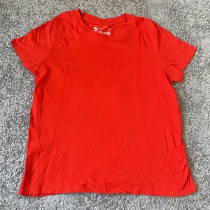 Röd/organge t-shirt  - En enkel och klassisk röd t-shirt. T-shirten har rund halsringning och korta ärmar. Perfekt basplagg att ha i garderoben och lätt att matcha med olika outfits.