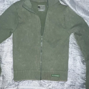 Grön ribbad ZIP UP från PrettyLittleThing🌴 - Säljer en grön ribbad tränings  Zip Up från PrettyLittleThing i storlek S. Jackan är tillverkad i ett stretchigt material med 92% polyamid och 8% elastan. 