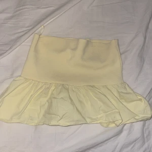 Ljusgul topp från ZARA - Supersöt ljusgul topp från ZARA med volang nertill. Topp har en tight passform upptill och är sydd i en mix av stickat och bomullstyg. Perfekt för dig som vill ha en feminin och trendig look.